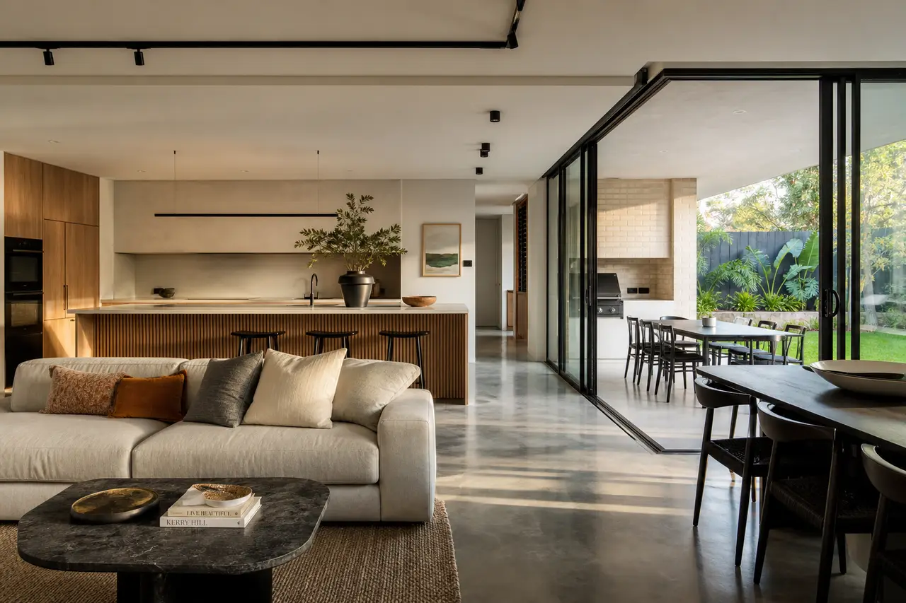 Wide editorial photograph of a modern Perth open-plan living room with continuous polished concrete floor extending into the kitchen, no people, photorealistic